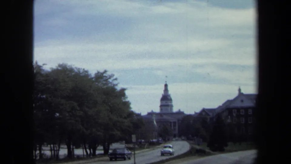 1970 8mm view of a Washington, DC street with trees, cars, and a distant domed civic building.