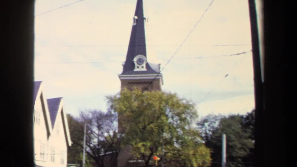 1970 Washington, DC 8mm frame showing the church steeple, clock opening, trees, bright sky, and neighboring building through a dark frame.