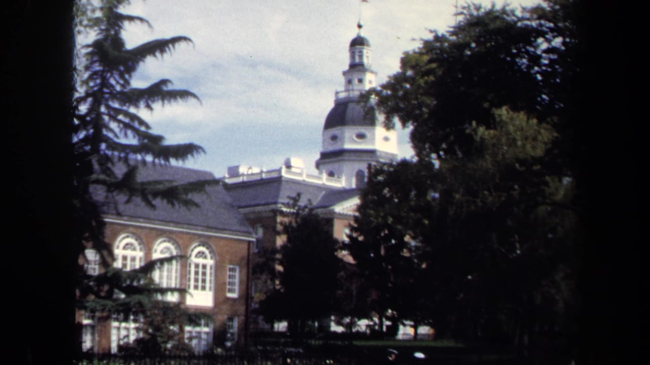 1970 8mm view of the Maryland State House dome and brick facade framed by trees and scan borders.