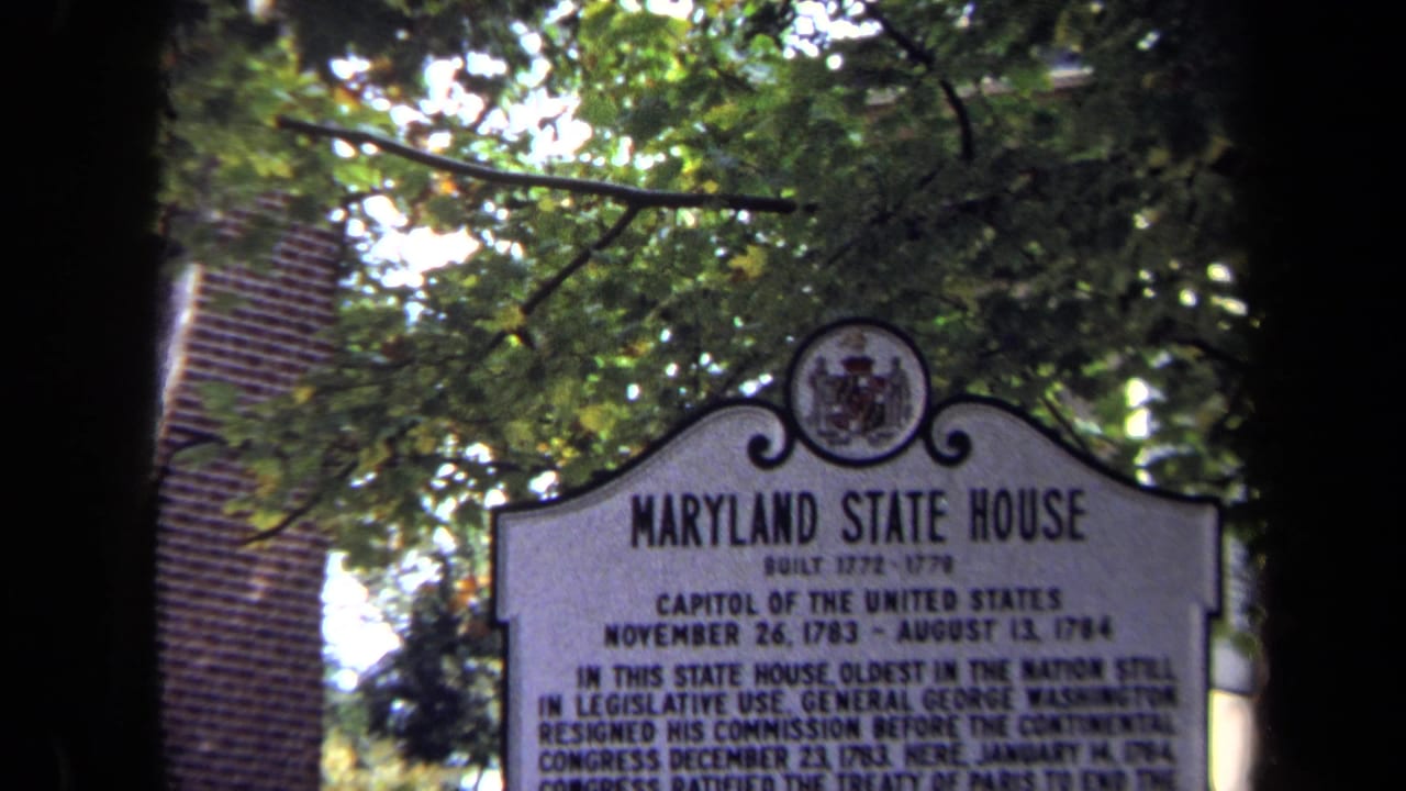 1970 8mm view of the Maryland State House marker, with its title readable above smaller historical text and trees overhead.