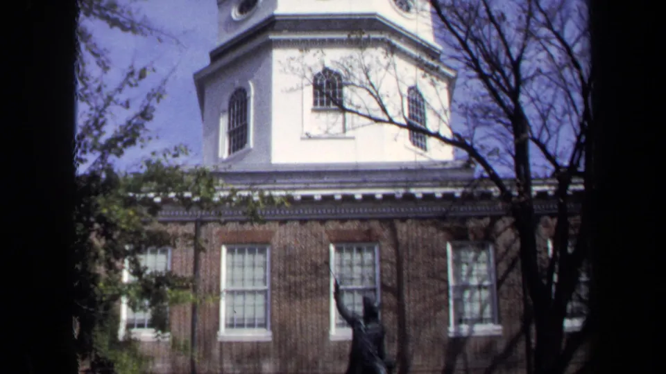 1970 Washington, DC 8mm frame showing the building cupola, upper brick facade, tree branches, and the DeKalb statue lower in view.