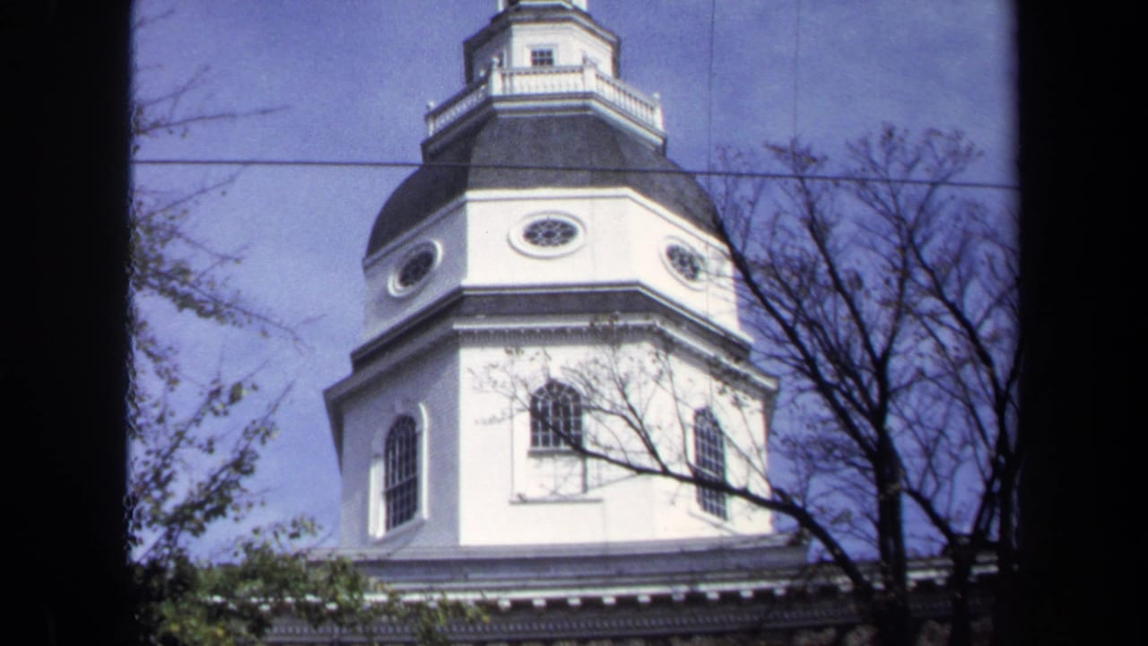 1970 Washington DC exterior frame of a white octagonal church tower with dark roof, lantern cupola, bare branches, utility wire, and blue sky.