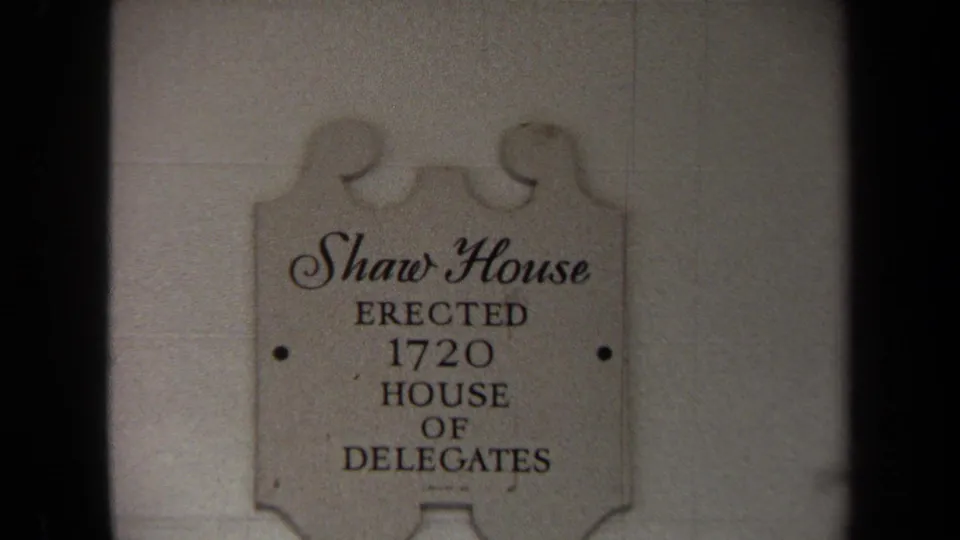 Close view of the Shaw House plaque on a light exterior wall, identifying the site and House of Delegates association.