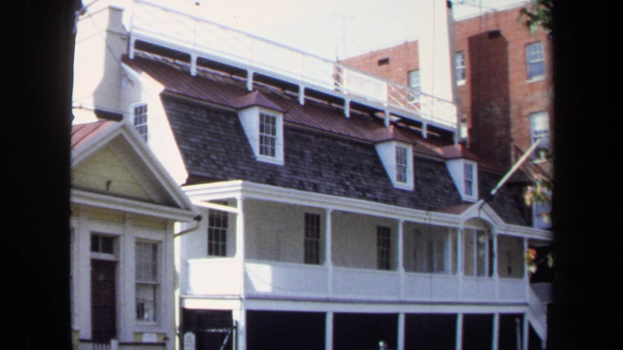 The 8mm frame holds on a Washington, DC row house exterior with white trim, a dark roof, dormers, and overhead utility lines.