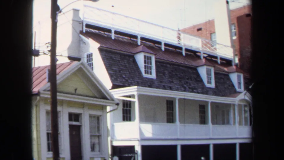 A closer 1970 Washington, DC view shows a yellow neighboring facade beside the white row house, with roof dormers and a utility pole visible.