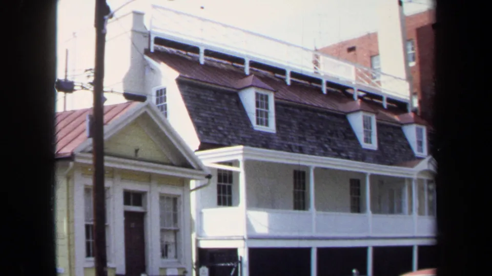 The final attached frame keeps the Washington, DC residential exterior in view, partly blocked by dark foreground edges and a utility pole.
