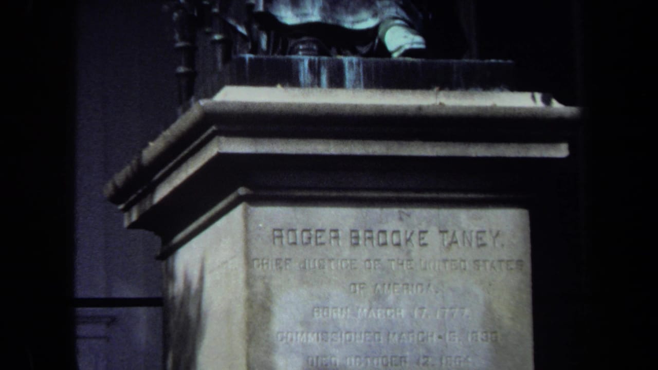 The pullback reveals more of the Roger Brooke Taney pedestal and the lower portion of the seated bronze statue above it.
