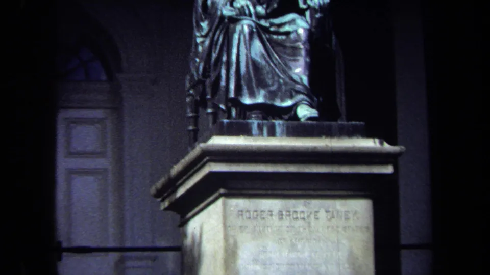 1970 Washington, DC frame showing the seated Taney statue on its pedestal with a doorway and dark wall behind it.