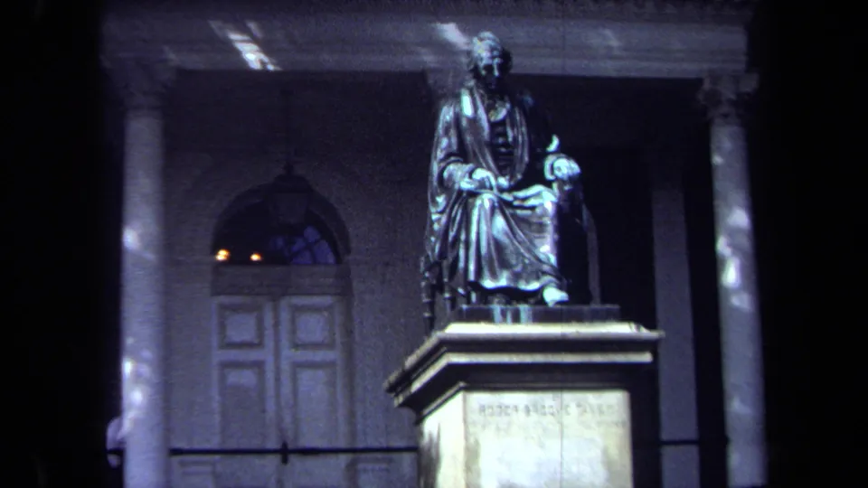 Wide 8mm view of the Roger Brooke Taney monument in Washington, DC, with columns, an arched doorway, and the pedestal visible below.