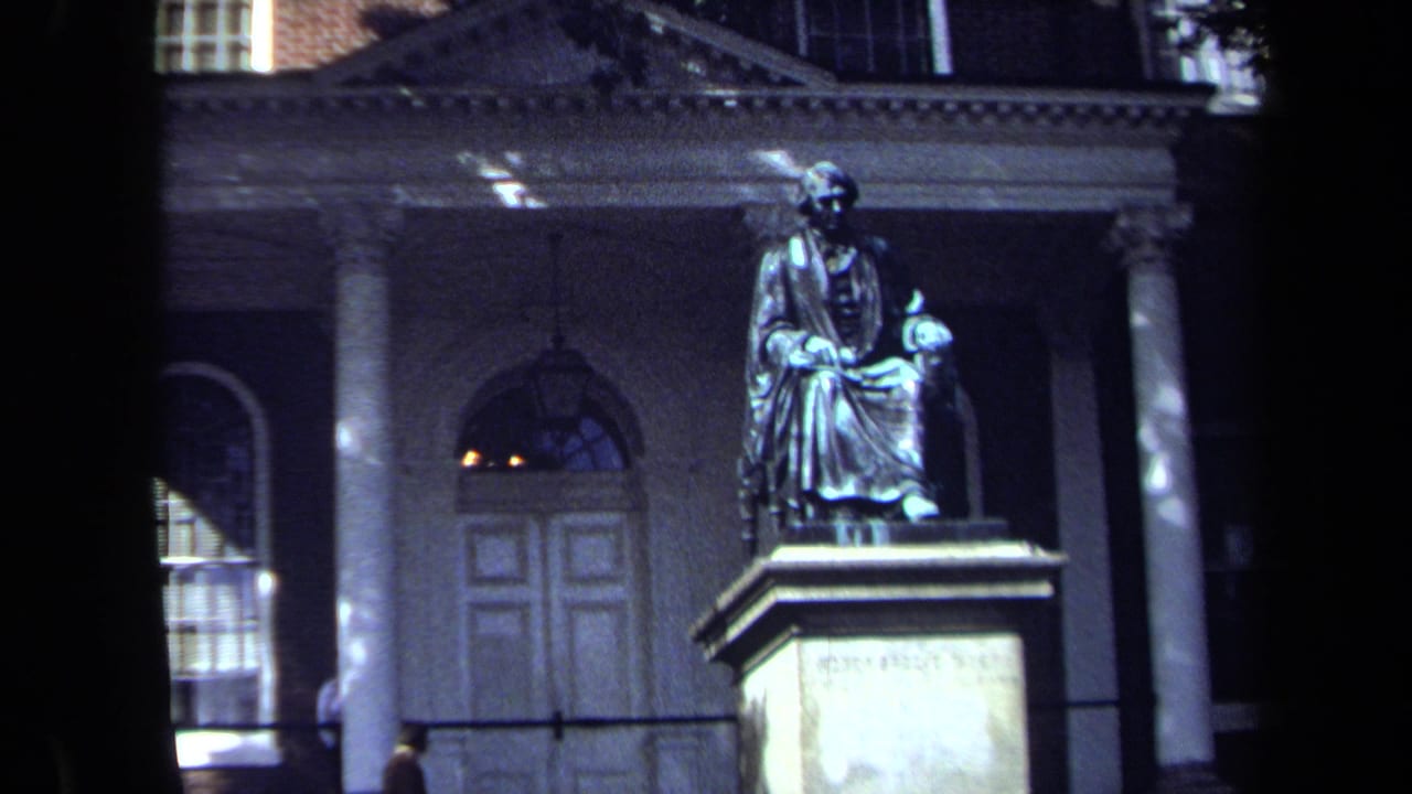 1970 Washington, DC home-movie frame showing a seated monument before a classical building with columns and an arched doorway.