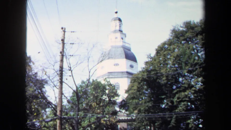 Handheld 1970 8mm view of the landmark cupola framed by trees, wires, and a foreground pole.