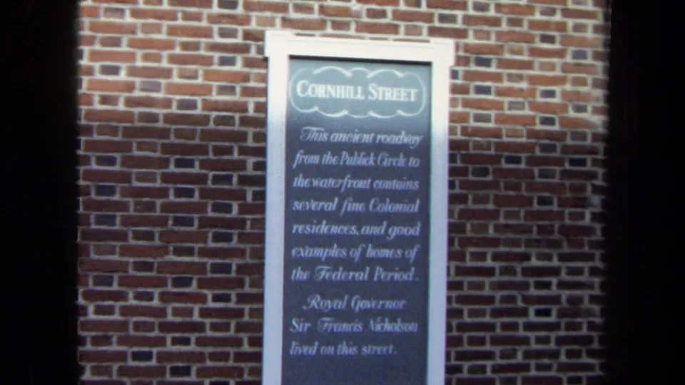 1970 8mm close view of a Cornhill Street historical plaque on a red brick wall.