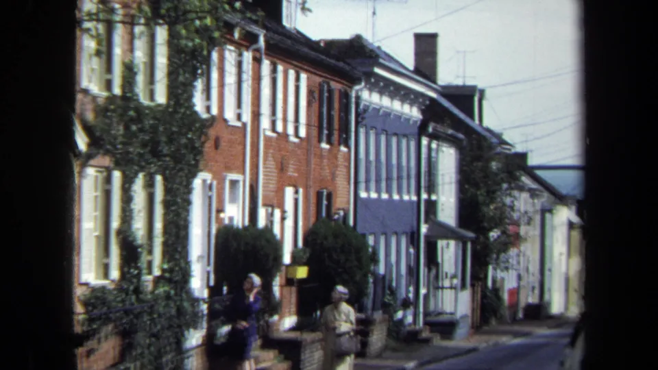 1970 Washington, DC home-movie frame with two women nearer the camera on a residential sidewalk.