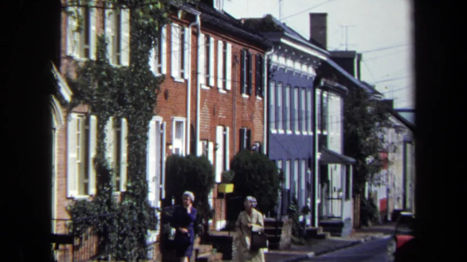 1970 Washington, DC residential frame showing two women on the sidewalk with row houses behind them.