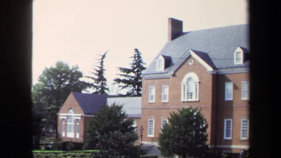 1970 Washington, DC frame showing a large brick building with dormer windows, a smaller brick structure, and landscaped trees.