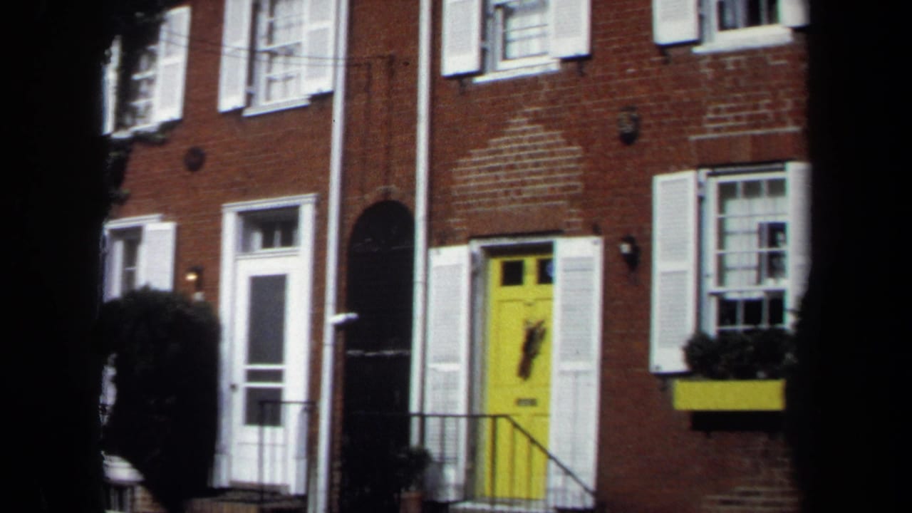 1970 Washington, DC view of brick row house fronts with yellow doors, white shutters, and a dark foreground band from the camera position.
