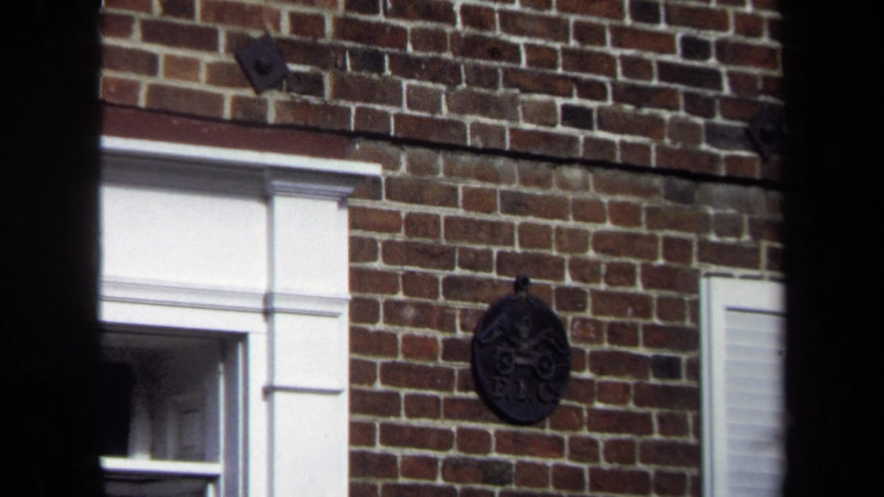 Closer brick facade with white trim, partial window, and dark decorative wall piece.