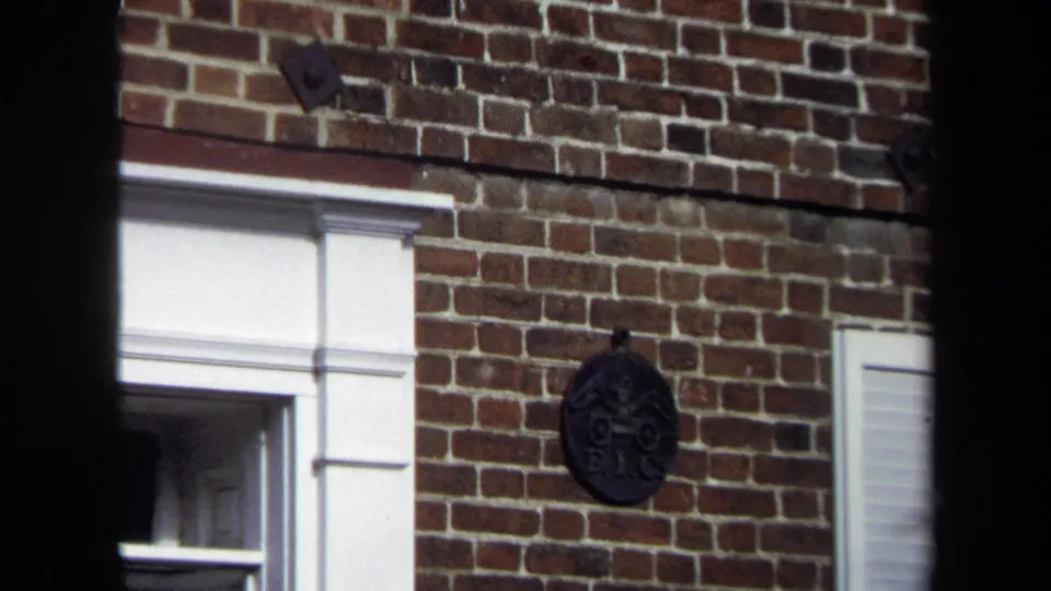 Brick exterior detail in the Washington, DC street scene, with white architectural trim and a dark decorative plaque or knocker on the wall.