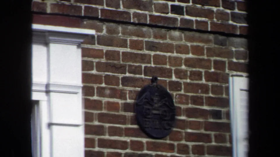 Close 8mm frame of a brick facade in Washington, DC, centered on a dark round wall ornament beside white trim.