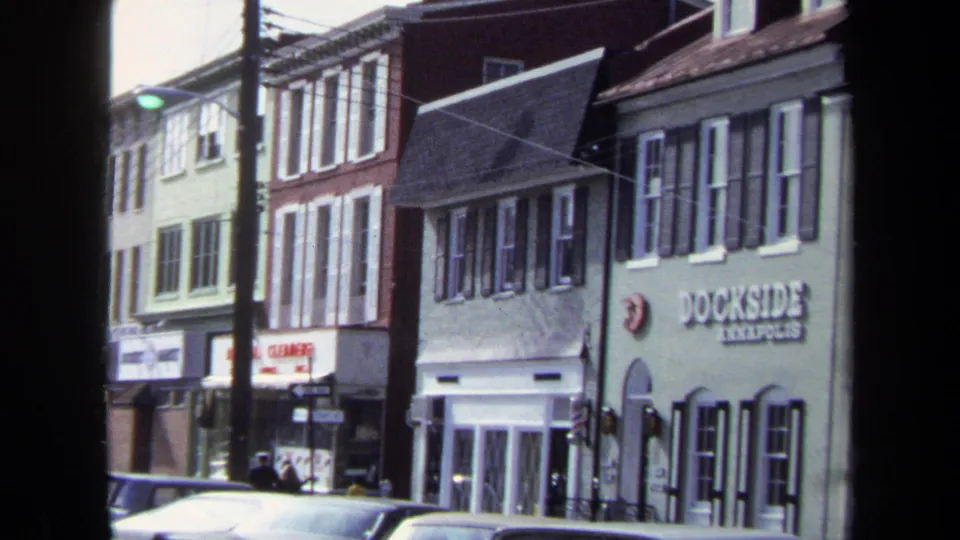 1970 Washington DC frame with the Dockside Annapolis sign visible on a light green building beside older storefronts and parked cars.