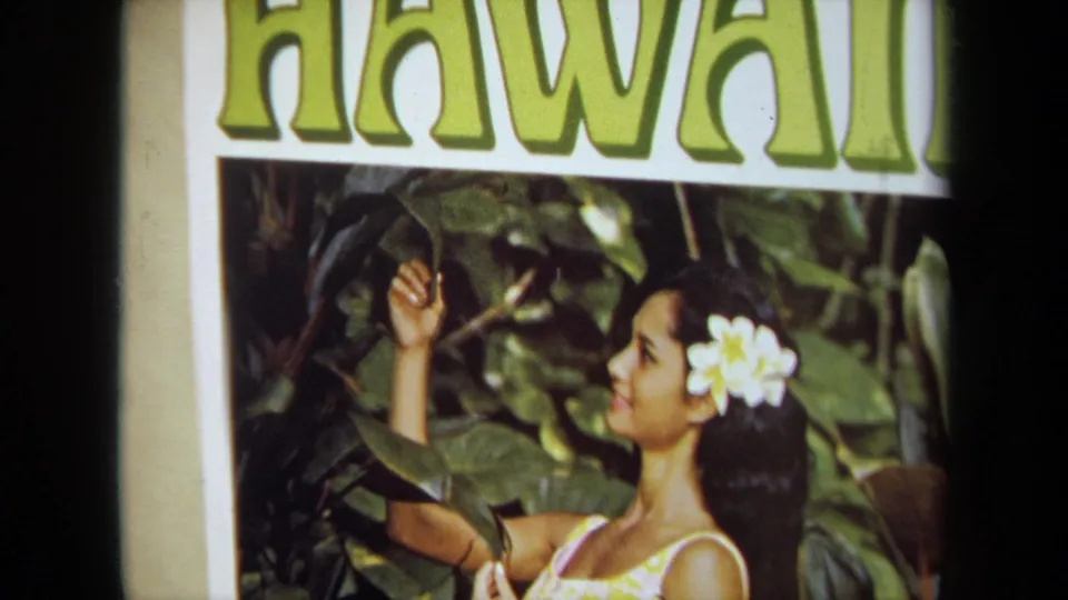 Close view of a HAWAII poster showing the same woman posed among tropical leaves, filmed in warm 8mm color.