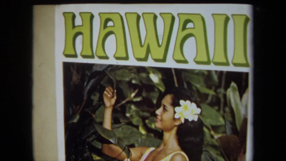1971 home-movie frame of a HAWAII poster, with bold green lettering over a woman posed in tropical foliage.