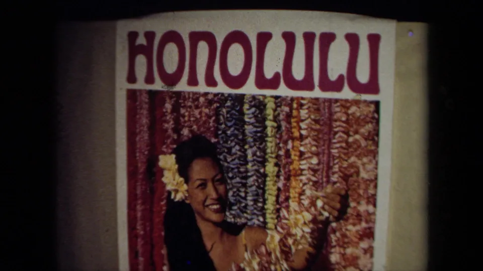 Close 8mm frame of a HONOLULU poster showing a smiling woman with a flower beside rows of colorful leis.