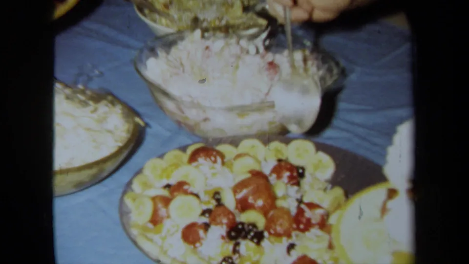 Close 8mm frame of an indoor buffet with creamy salads and a fruit platter, supported by 1971 California clip metadata.