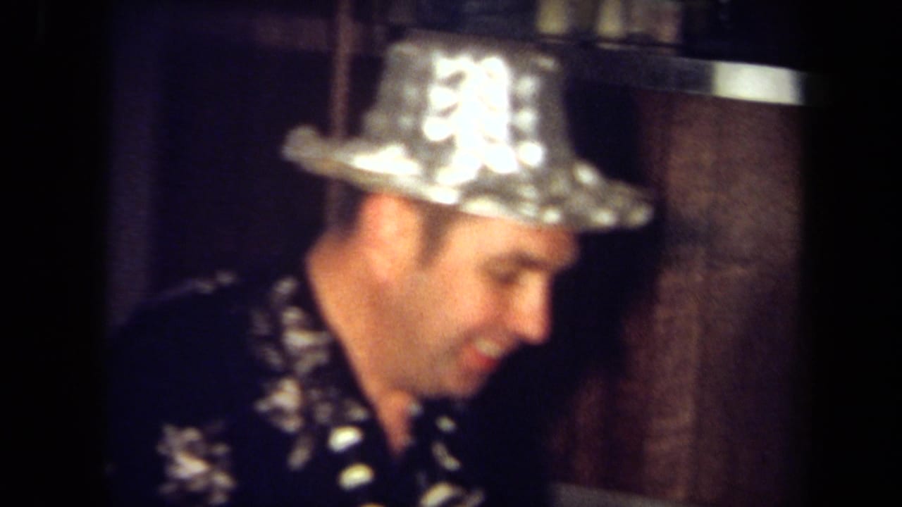 Soft close view of a man wearing a shiny foil hat in a wood-paneled interior.