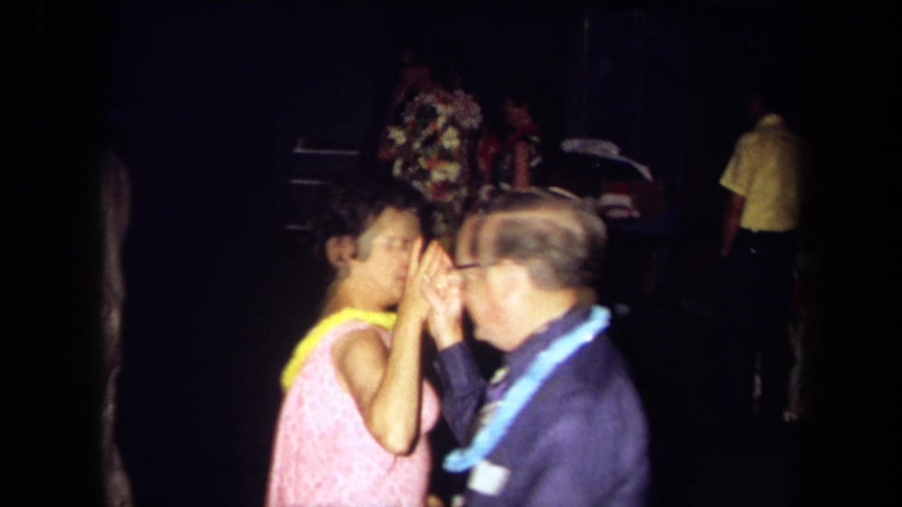 In 1971 California home-movie footage, adults in leis appear to dance at a Hawaiian-themed indoor party.