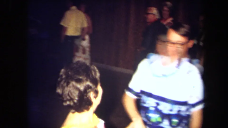 Motion blur from the 8mm camera catches an adult dancer moving through the private party interior.