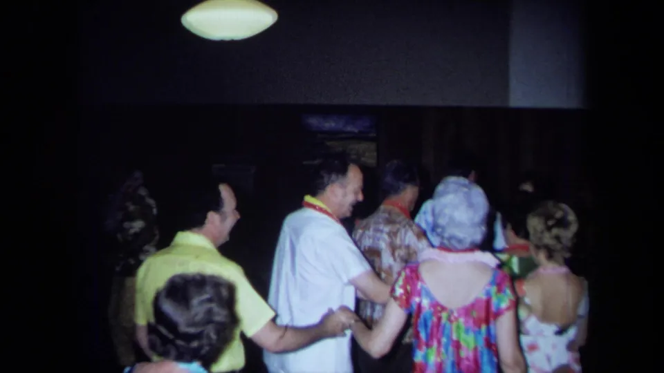 Adults wearing leis and tropical-print attire dance closely in a dim California indoor party setting, supported by 1971 metadata.