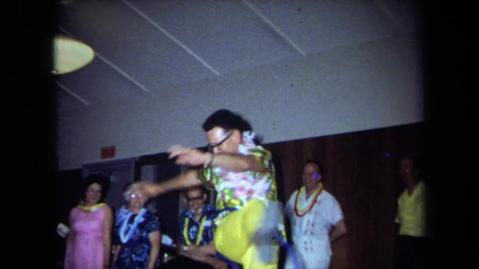 A 1971 California party scene shows a man in a colorful outfit hula-hooping energetically while adults watch from the wall.