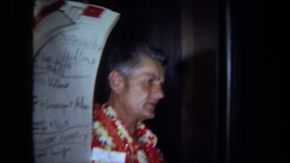 A man in a red aloha shirt and lei appears beside a handwritten program sheet in the 1971 indoor party footage.