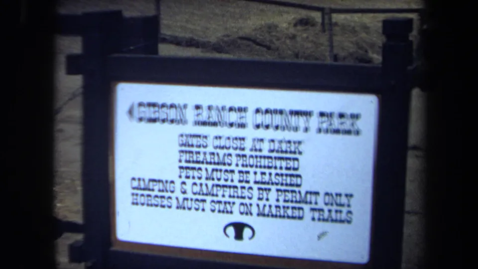 Close view of a Gibson Ranch County Park sign listing visitor rules, with fencing and ground visible behind it.