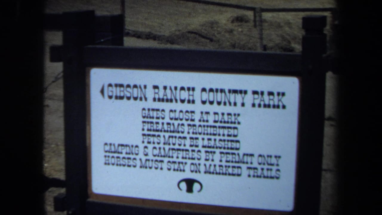 White Gibson Ranch County Park rules sign framed by dark posts.