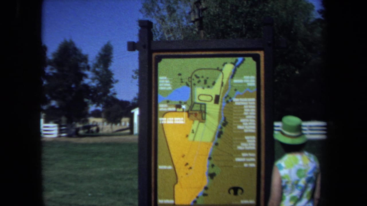 Woman seen from behind beside an illustrated park map with a grassy area in the background.