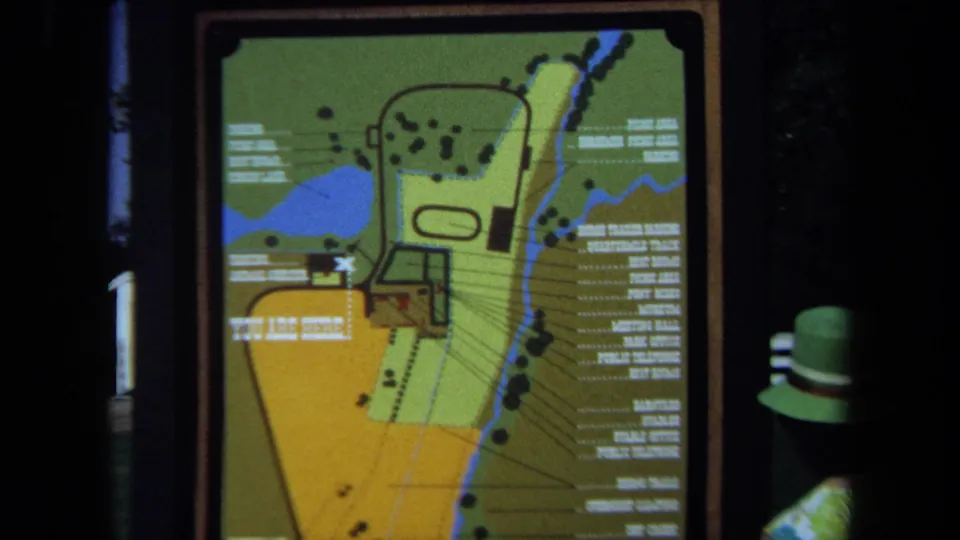 The final frame centers the colorful park map sign, while the woman’s green hat and shoulder remain visible at the lower right.
