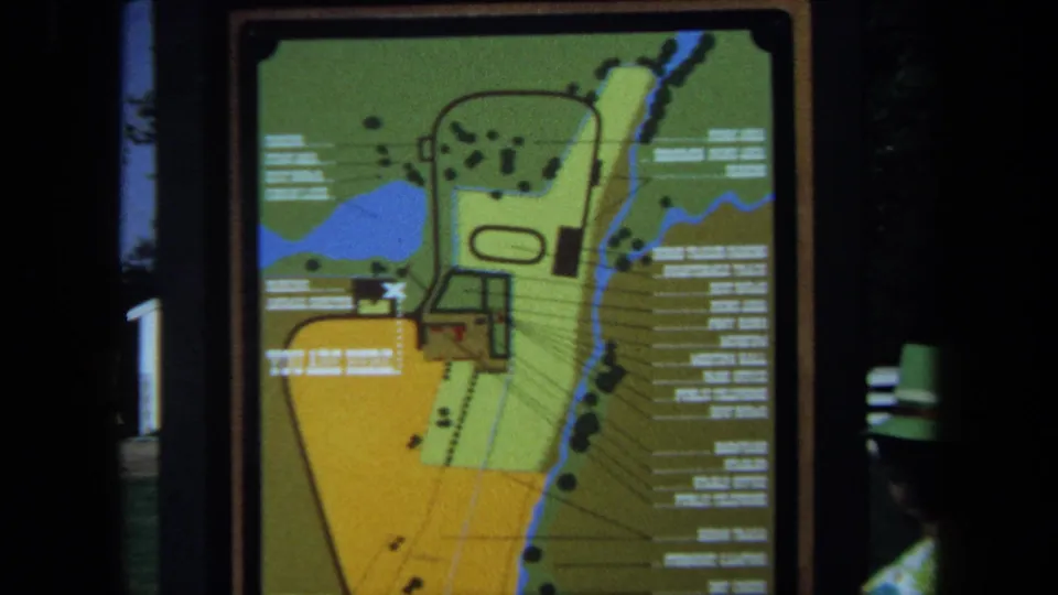 1971 California park map sign remains in view, with colored grounds, printed labels, paths, and a partial visitor at the edge.