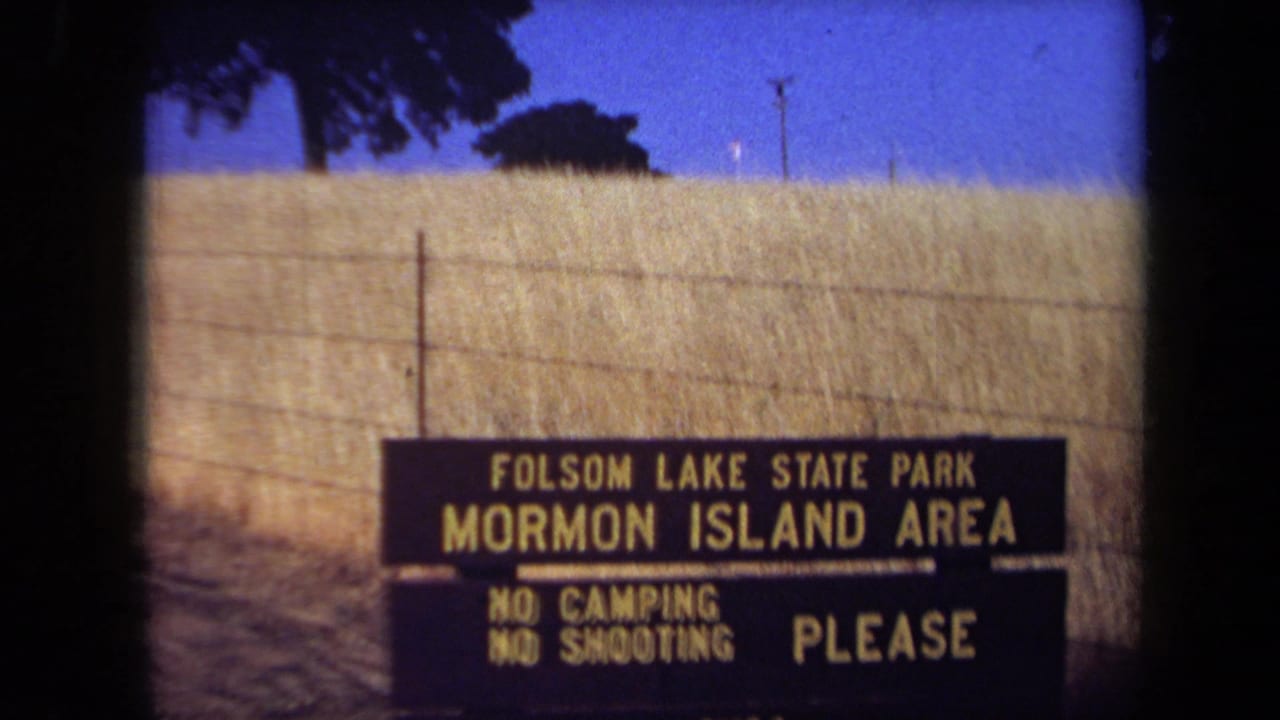 Mormon Island Area sign beside a dry field, fence, trees, and blue sky.