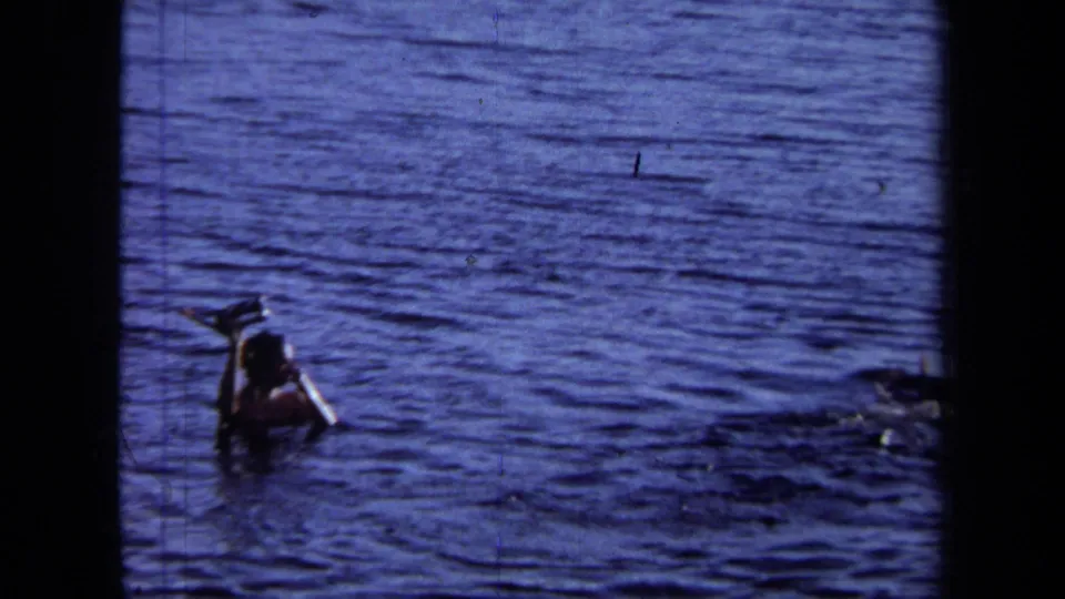In 1971 California home-movie footage, a person swims in deep blue water while holding what appears to be a camera above the surface.