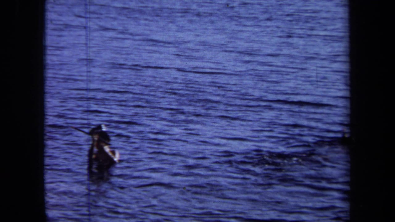 Person standing or swimming in open water with another swimmer distant nearby.