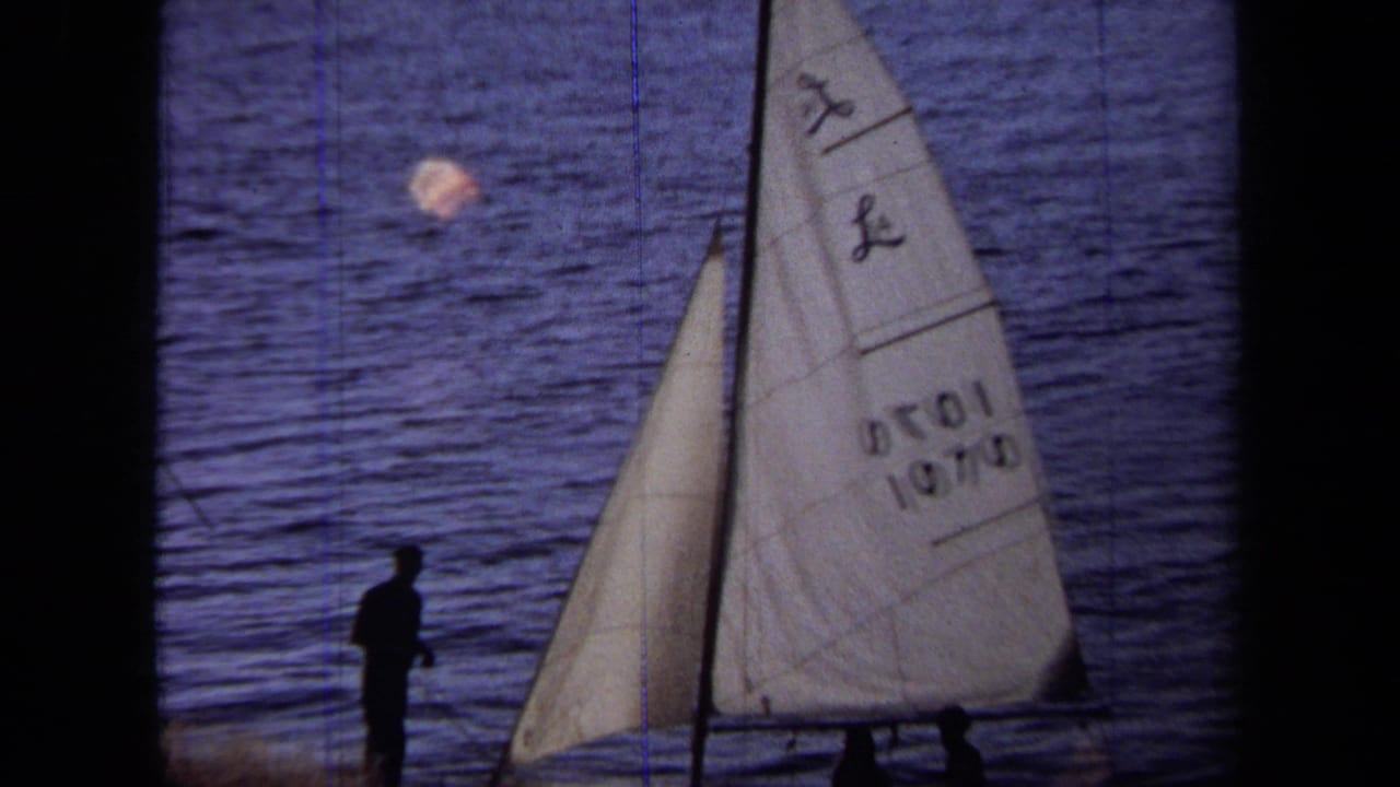 1971 California 8mm frame with a silhouetted man near the water and a small sailboat carrying a white sail marked 1070.