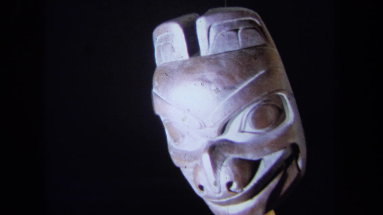 1971 California 8mm frame showing a carved wooden mask facing forward under direct light against a dark background.