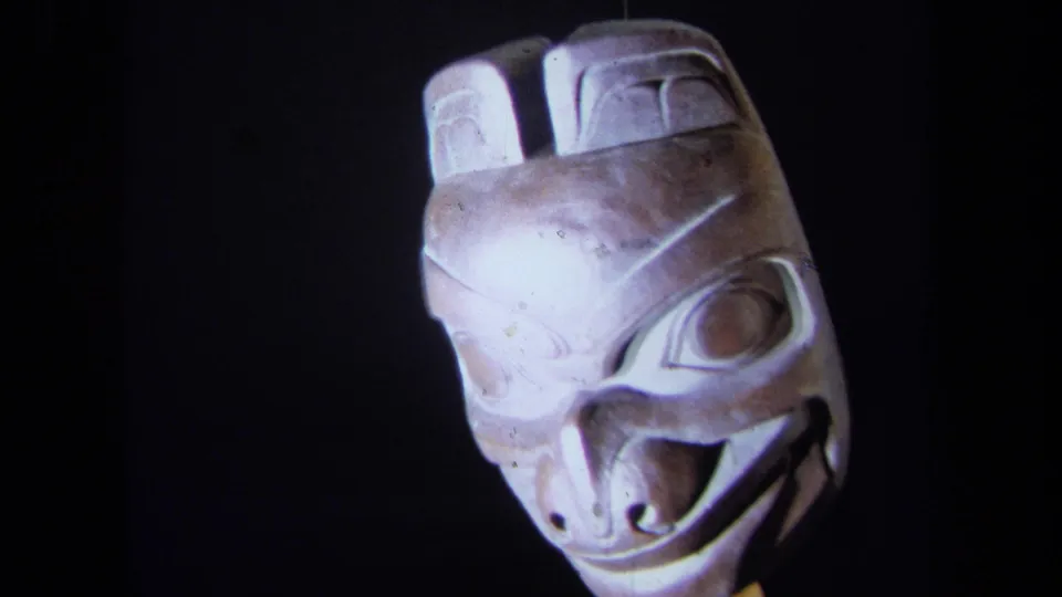 1971 California 8mm frame showing a carved wooden mask facing forward under direct light against a dark background.