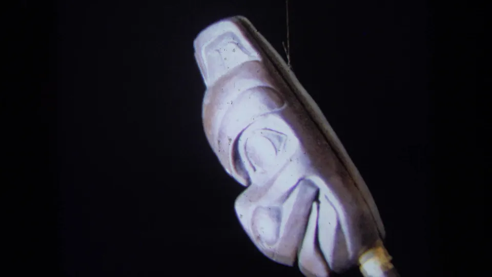 1971 California 8mm frame showing the carved mask turned to a side profile, revealing its projecting form.