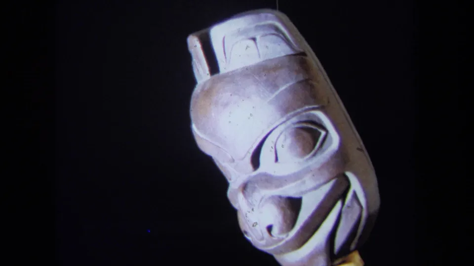 1971 California 8mm frame showing the carved wooden mask at a three-quarter angle with visible eye and mouth details.