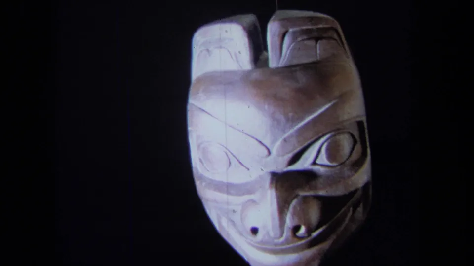 1971 California 8mm frame showing the mask near a frontal view, with carved eyes and mouth lit from above or front.