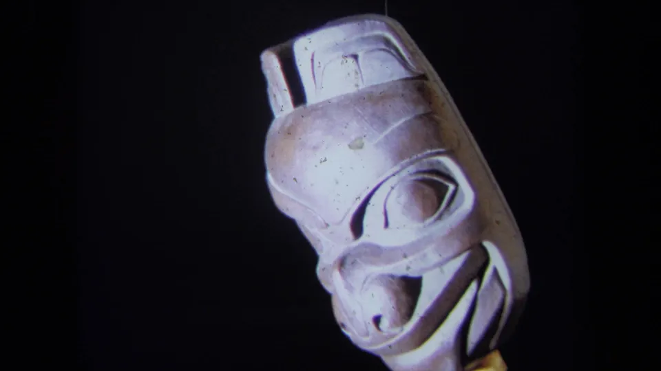 Close 1971 8mm view of the carved mask, with the face turned slightly and surface marks visible under direct light.