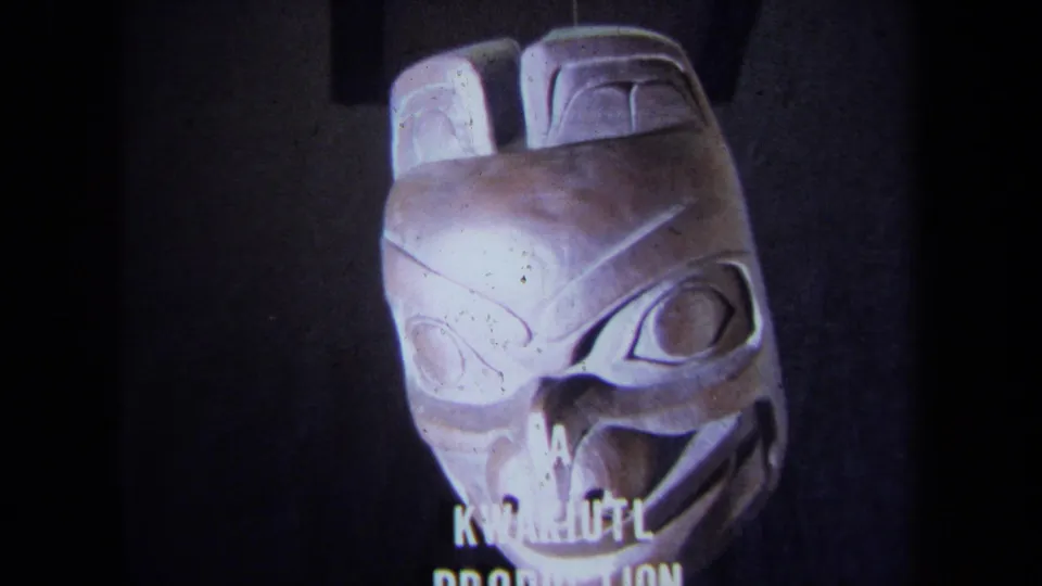 The carved mask remains in close-up while partial white end text appears below, consistent with the clip's museum or production-card context.